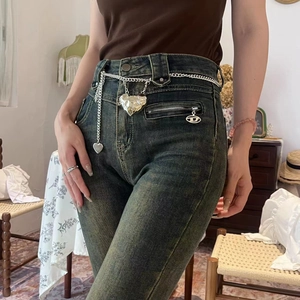 Close-up of heart-shaped silver chain accessory hanging on vintage denim jeans pocket