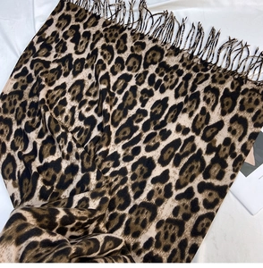 Close-up of leopard print scarf fabric texture and fringe detail on white background