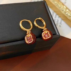 Makroaufnahme von Granatapfel-Ohrringen mit roter Emaille und Zirkon auf Box
