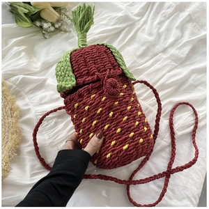 Macro detail of handmade strawberry woven crossbody bag with green leaf and seed texture
