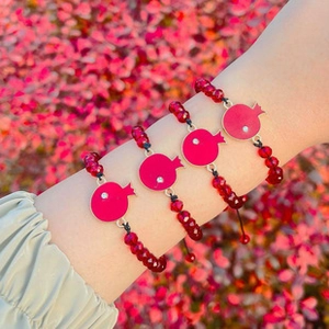 Close-up of golden pomegranate charms with red beads and sparkling crystal detail