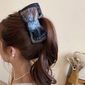 Detail of checkered mohair bow hair clip worn on a low ponytail for elegant winter styling