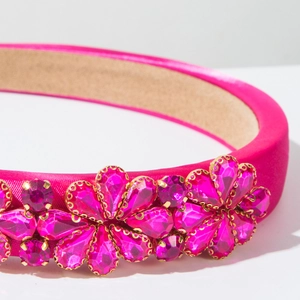 Nahaufnahme eines fuchsiafarbenen Satin-Stirnbands mit funkelnden Kristallblumenmustern