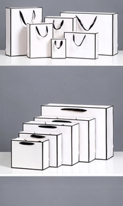 Detailed view of white paper gift bags with black edges and ribbon handles in various sizes