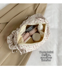 Detailed view of the large capacity floral makeup bag with cream lining and red blossoms