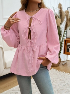 Detail of red and white striped blouse with V-neckline, lace-up cutouts and lantern sleeves