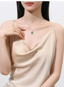 Close-up of S925 sterling silver necklace featuring a green emerald-cut pendant on model