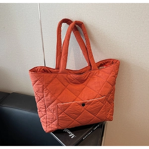 Detail of orange quilted tote bag with diamond pattern and external snap pocket
