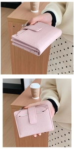 Close-up of pink woven texture wallet with snap button closure on a wooden table