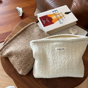 Detailed macro view of beige and brown tweed cosmetic bags with zipper on wooden table