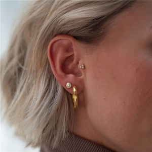 Close-up of pearl studs and gold hoop earrings on ear for a minimalist jewelry set look