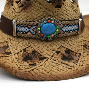 Détail d'un chapeau de cowboy en paille avec bande en cuir et pierre turquoise bohème