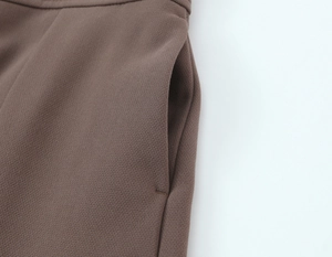 Gros plan détaillé du pantalon fuselé marron montrant les coutures de la poche et le tissu