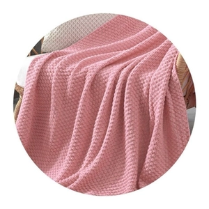 Macro view of pink waffle weave knit blanket with soft texture on a wicker chair