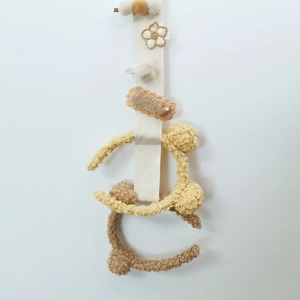 Wall-mounted cream hair accessory organizer with plush bear details and clips
