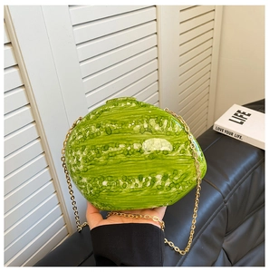 Detail of a watermelon shaped green acrylic clutch bag with a golden metal chain strap