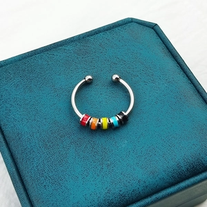 Close-up of a silver spinning ring with colorful enamel beads on a blue display box