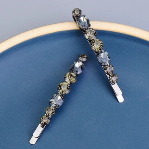 Gros plan de barrettes à strass étincelants gris foncé et vert lime sur un plat en céramique