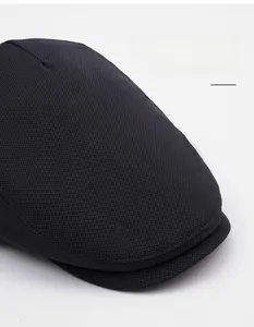 Detail of dark grey knitted newsboy cap featuring wide brim for face contouring effects