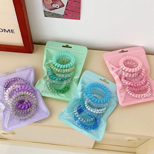 Detail of spiral hair ties in assorted gradient colors within frosted zip-lock packaging