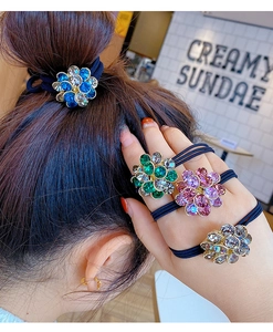 Detail of crystal flower hair ties in blue, green, pink, and grey on a model's wrist