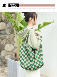Detail of green checkerboard canvas tote bag worn by model in a stylish outdoor setting