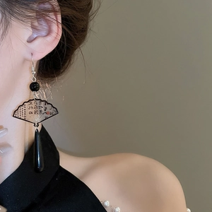 Detail of traditional Chinese ink fan earrings with black waterdrop pendants on a model