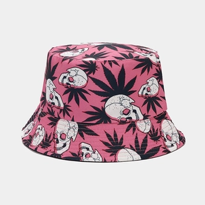 Detailed close-up of pink bucket hat with white skull and green leaf patterns on canvas