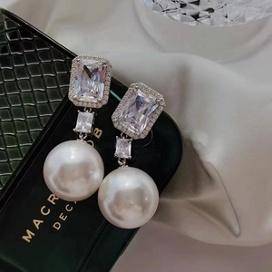 Elegant drop earrings featuring large rectangular zircons and round pearls on a jewelry box