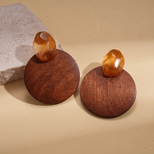 Gros plan de boucles d'oreilles géométriques en bois et résine ambre sur pierre