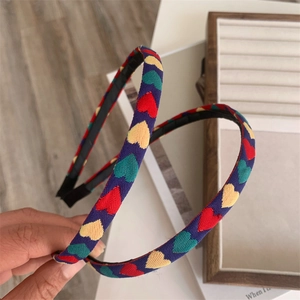 Detailed shot of a navy woven headband featuring colorful embroidered heart patterns