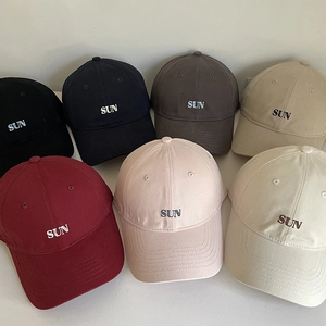 Detail shot of multi-colored cotton baseball caps with SUN embroidery in seven colors