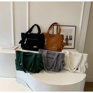 Corduroy tote bags in five colors displayed on a modern minimalist white tiered stand
