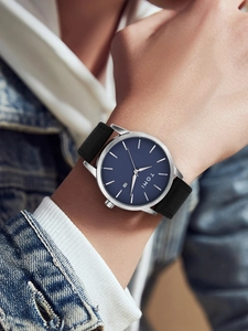Close-up of TOMI watch with deep blue dial, date window and black matte strap on wrist