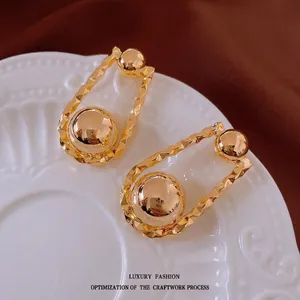 Minimalist gold plated spherical earrings with wavy metal frames on elegant display