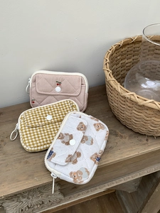 Quilted cotton card pouches with cherry, plaid, and bear patterns on a rustic wooden table