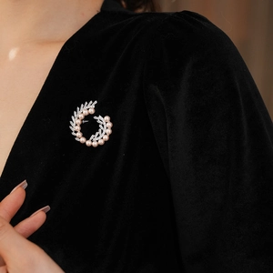 Detail of a spiral brooch with pink pearls and zircon crystals on black velvet clothing