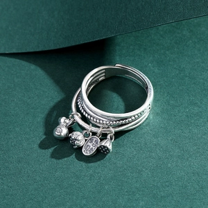 Detailed view of silver layered open ring with small lotus and money bag charms