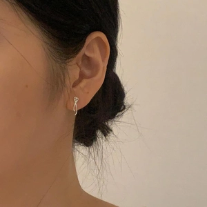 Close-up of minimalist sterling silver knot stud earrings worn by a model