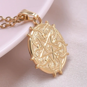 Macro shot of 18k gold plated round pendant featuring star and snake relief details