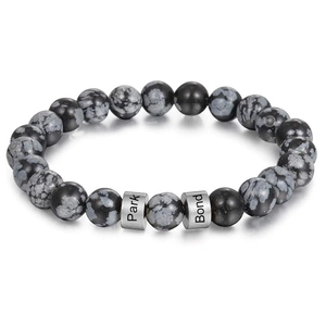 Detailed shot of snowflake obsidian beads with custom engraved stainless steel cylinders