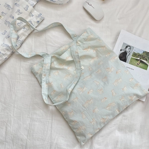 Detail of light blue canvas tote bag with cute orange cat print and long shoulder straps