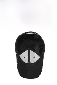 Detail of black breathable baseball cap with embroidered white fashion letters on the brim