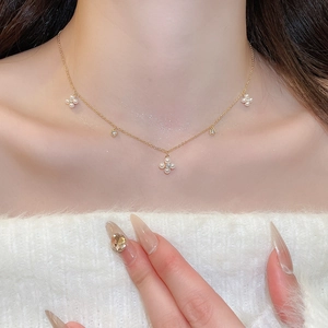 Close-up of gold-plated necklace with pearl flowers and zircon studs on a model