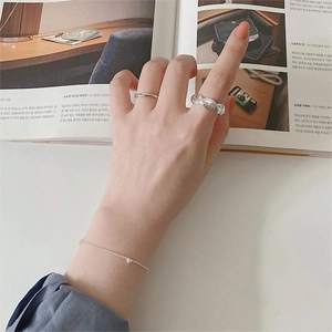 Close-up of 925 sterling silver minimalist rings and heart pendant bracelet on model hand