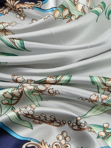 Macro detail of silk-feel scarf fabric featuring lily and golden baroque patterns