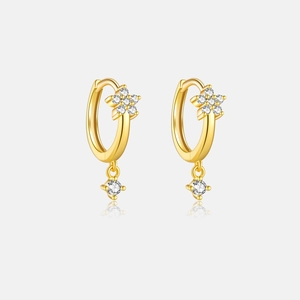 Detailed macro view of gold flower earrings featuring a sparkling round zircon pendant