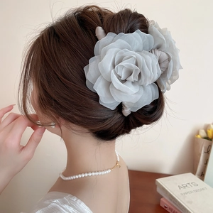 Détail d'une pince à cheveux rose en tissu gris élégante portée avec des perles