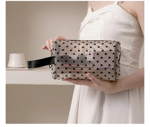 Close-up of transparent mesh makeup bag featuring black flocked hearts and a sturdy handle
