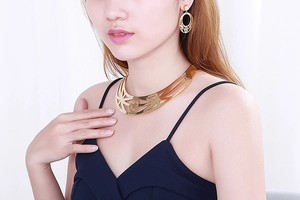Close-up of gold choker necklace and pearl earrings set with hollow star pattern on a model